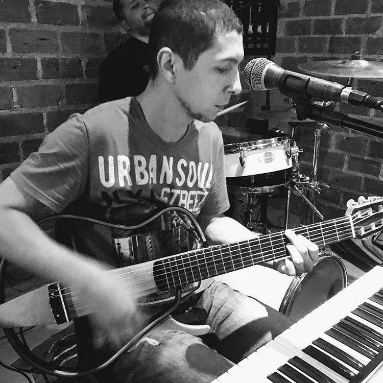 Gean Pacheco tocando violão e teclado com a banda